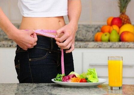 Seorang gadis menurunkan berat badan semasa diet mengukur saiz pinggangnya